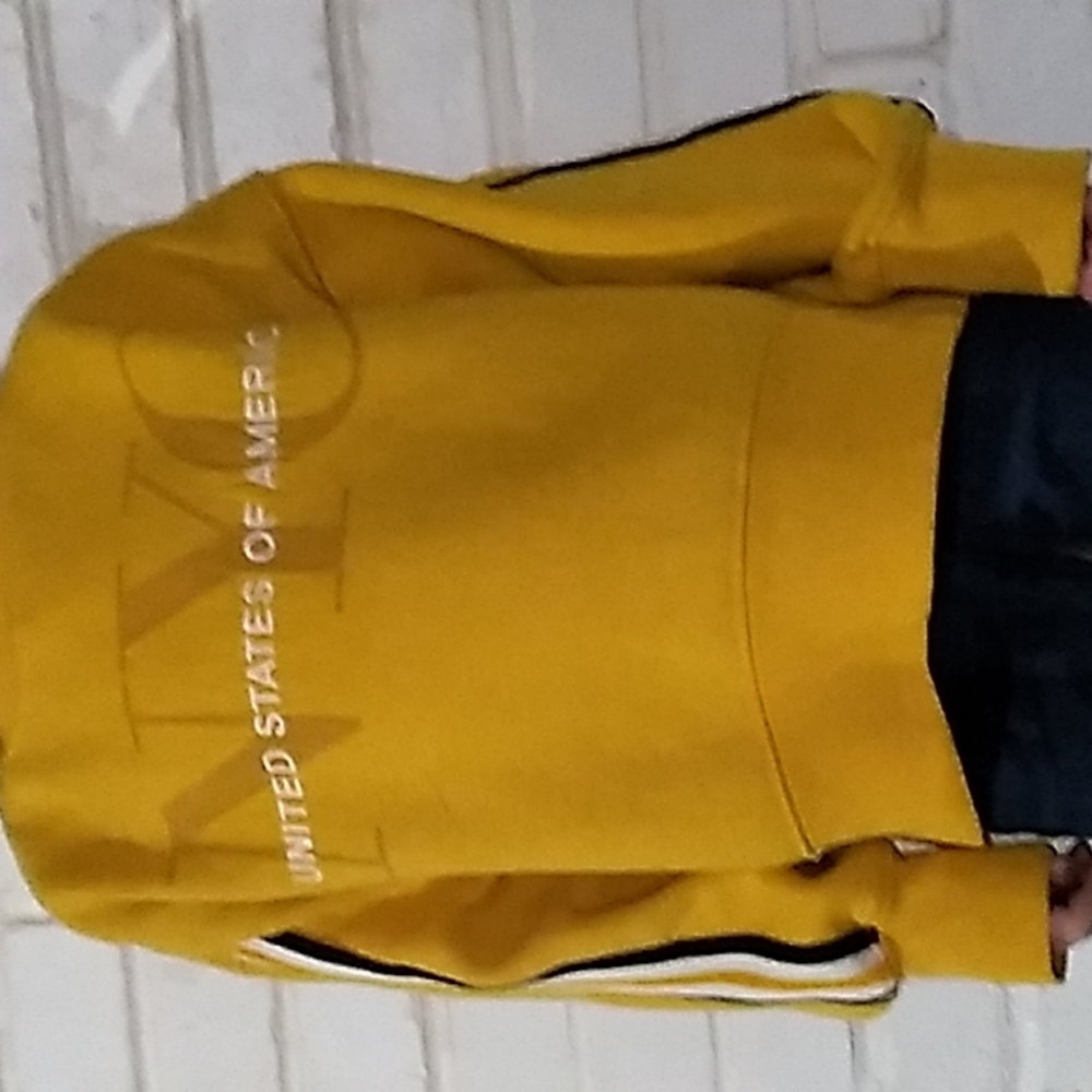 A yellow swet shirt with black white organ strips on both sides
